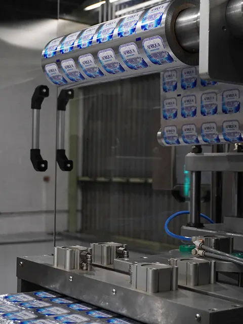 A roll of printed Afriqua foil lids feeding into the sealing machine