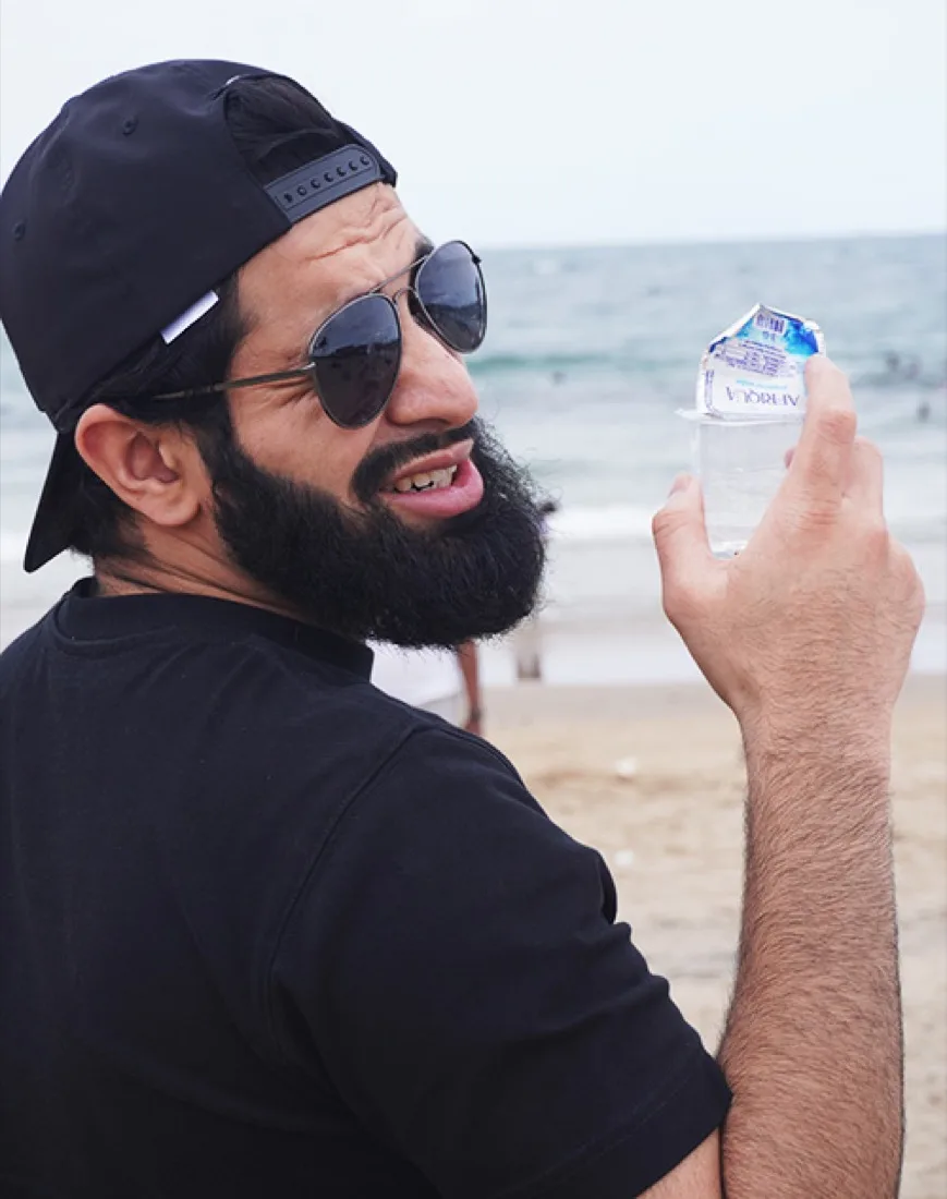 A man enjoying a sealed Afriqua water cup at the beach