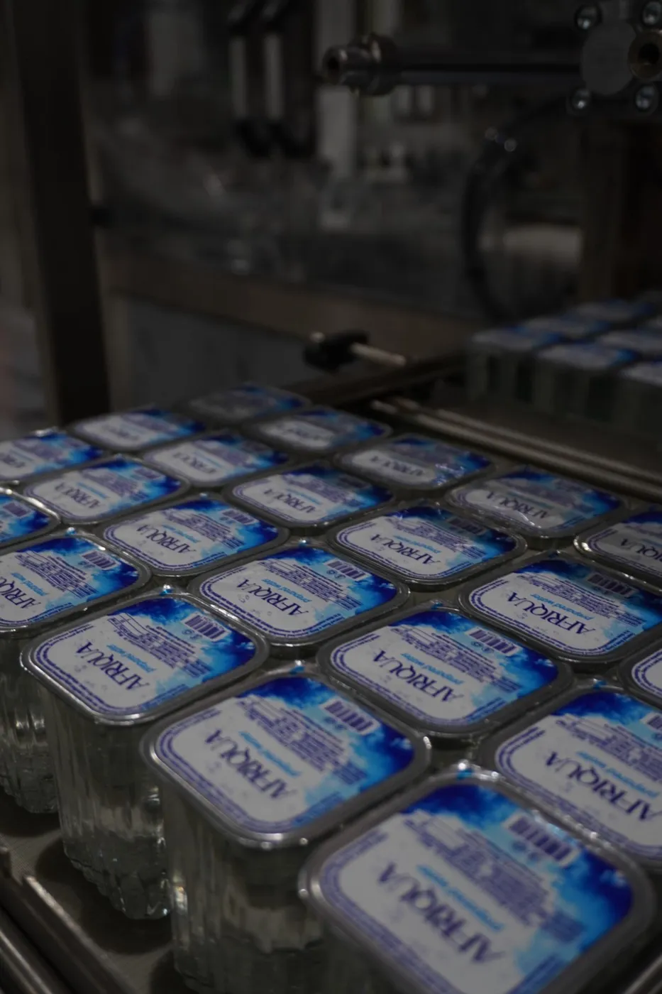 Trays of foil-sealed Afriqua water cups moving along the production line